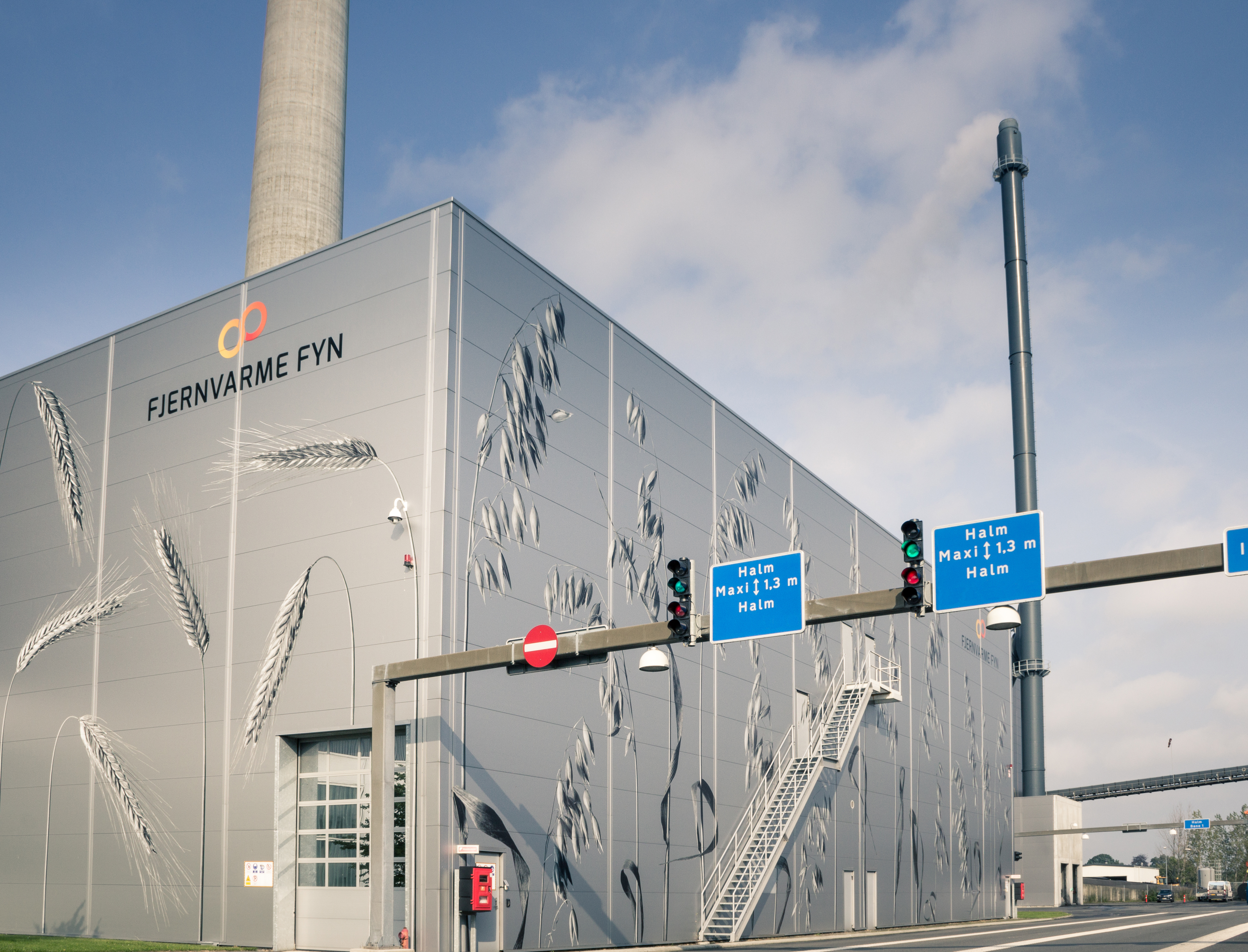 Exterior view of the Fjernvarme Fyn straw-fired power plant building with grain illustrations on the facade, highlighting a ServiceNow implementation.