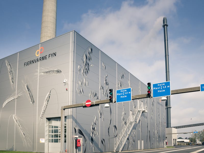 Exterior view of the Fjernvarme Fyn straw-fired power plant building with grain illustrations on the facade, highlighting a ServiceNow implementation.