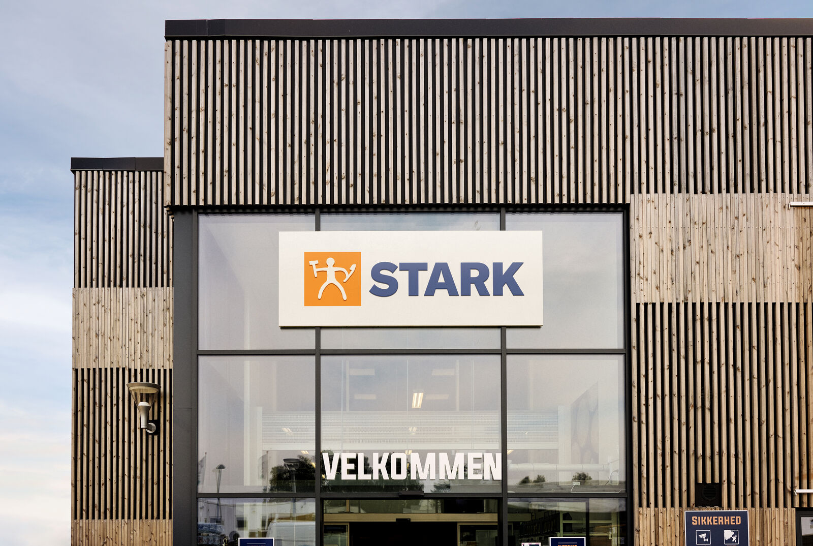 Exterior of a STARK store with wooden slat walls and a glass entrance, featuring a ServiceNow solution.
