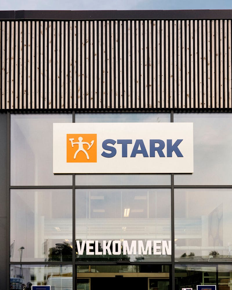 Exterior of a STARK store with wooden slat walls and a glass entrance, featuring a ServiceNow solution.