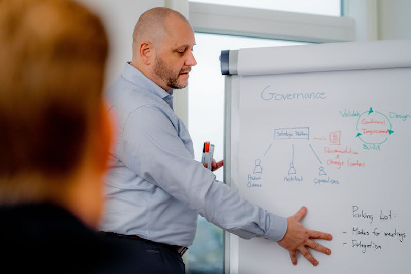 A man presenting a governance and strategic platform diagram on a whiteboard during a ServiceNow workshop.