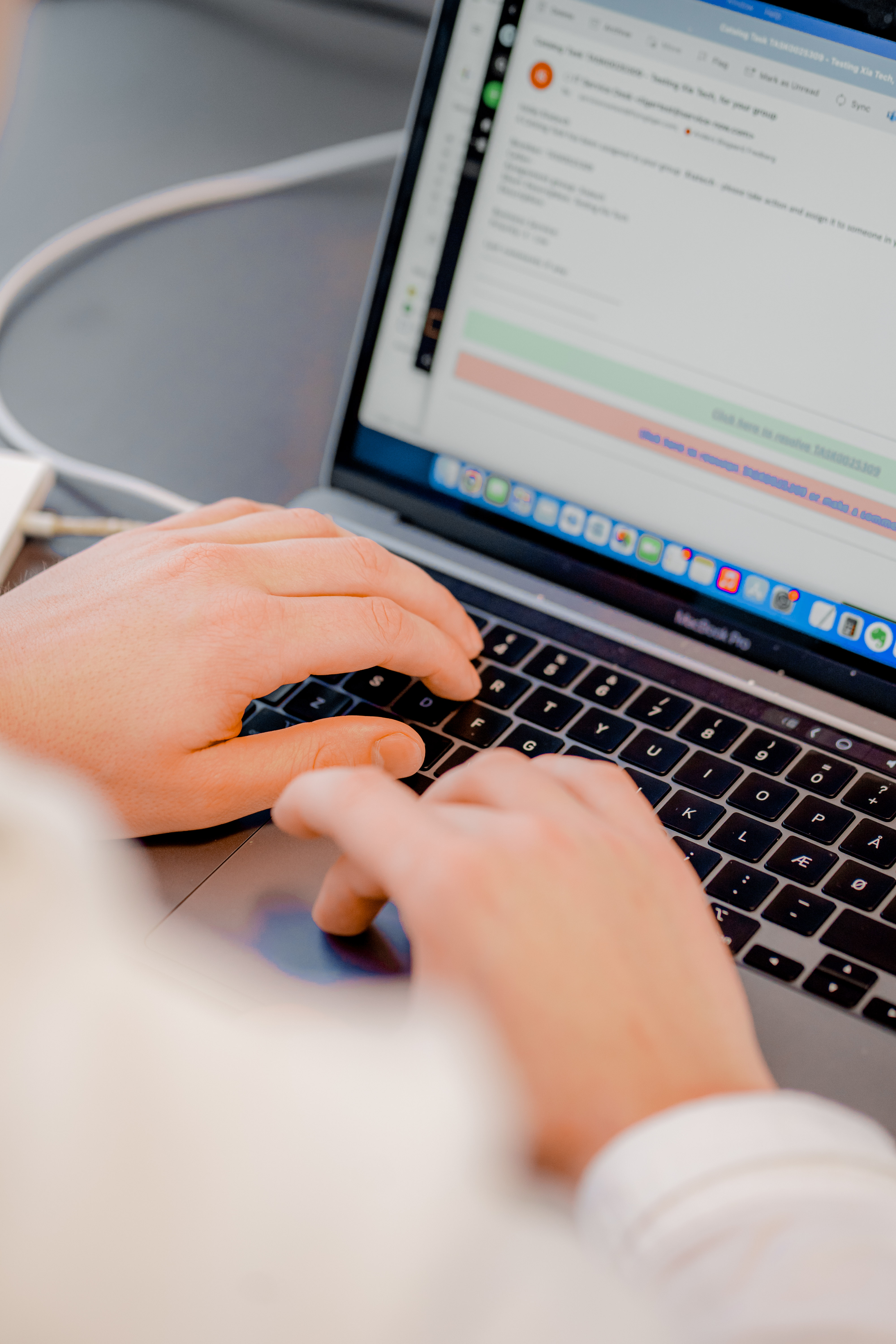 Hands typing on a laptop keyboard displaying the ServiceNow interface.