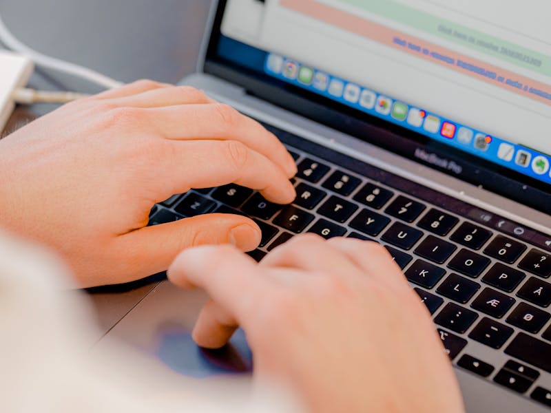 Hands typing on a laptop keyboard displaying the ServiceNow interface.