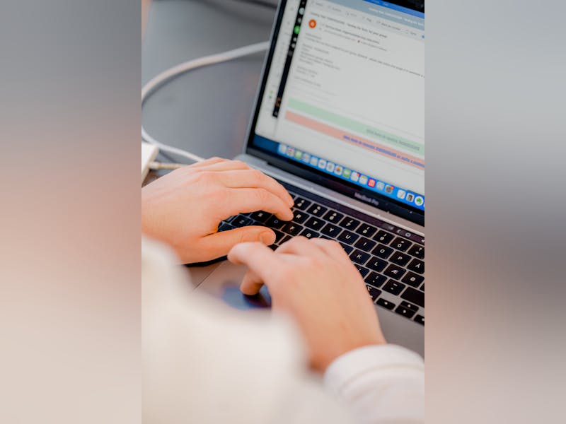 Hands typing on a laptop keyboard displaying the ServiceNow interface.