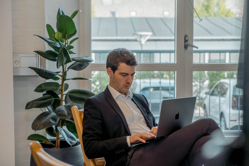 A man in a suit working on a laptop in an office, representing a ServiceNow professional.