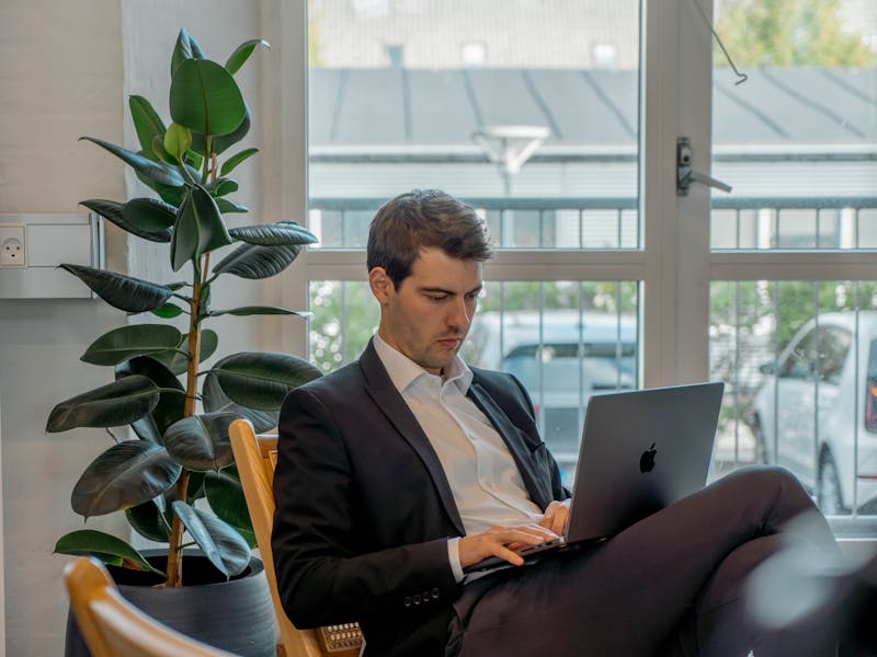 A man in a suit working on a laptop in an office, representing a ServiceNow professional.