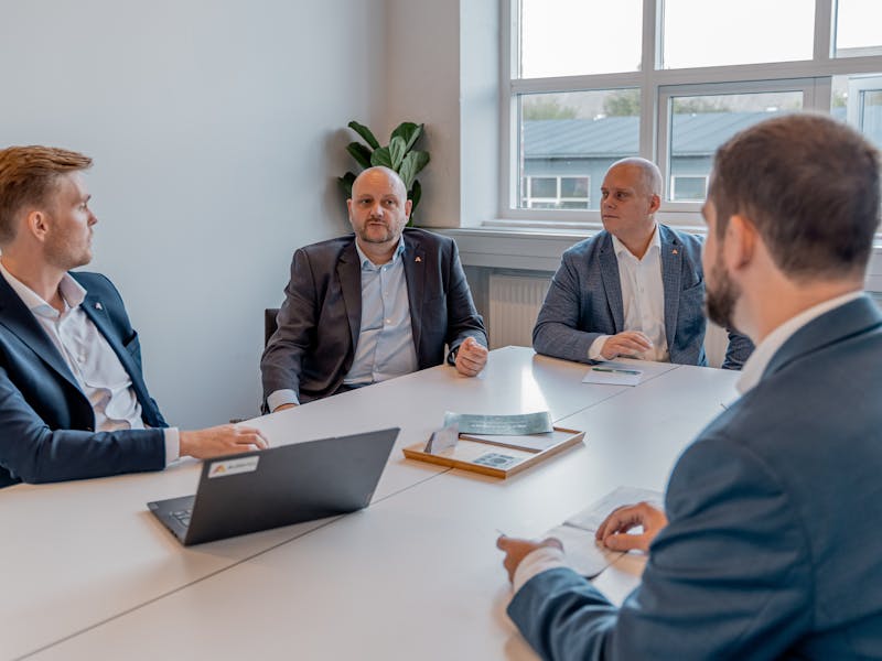 Five professionals in business attire sitting around a conference table at ServiceNow partner Adeno.