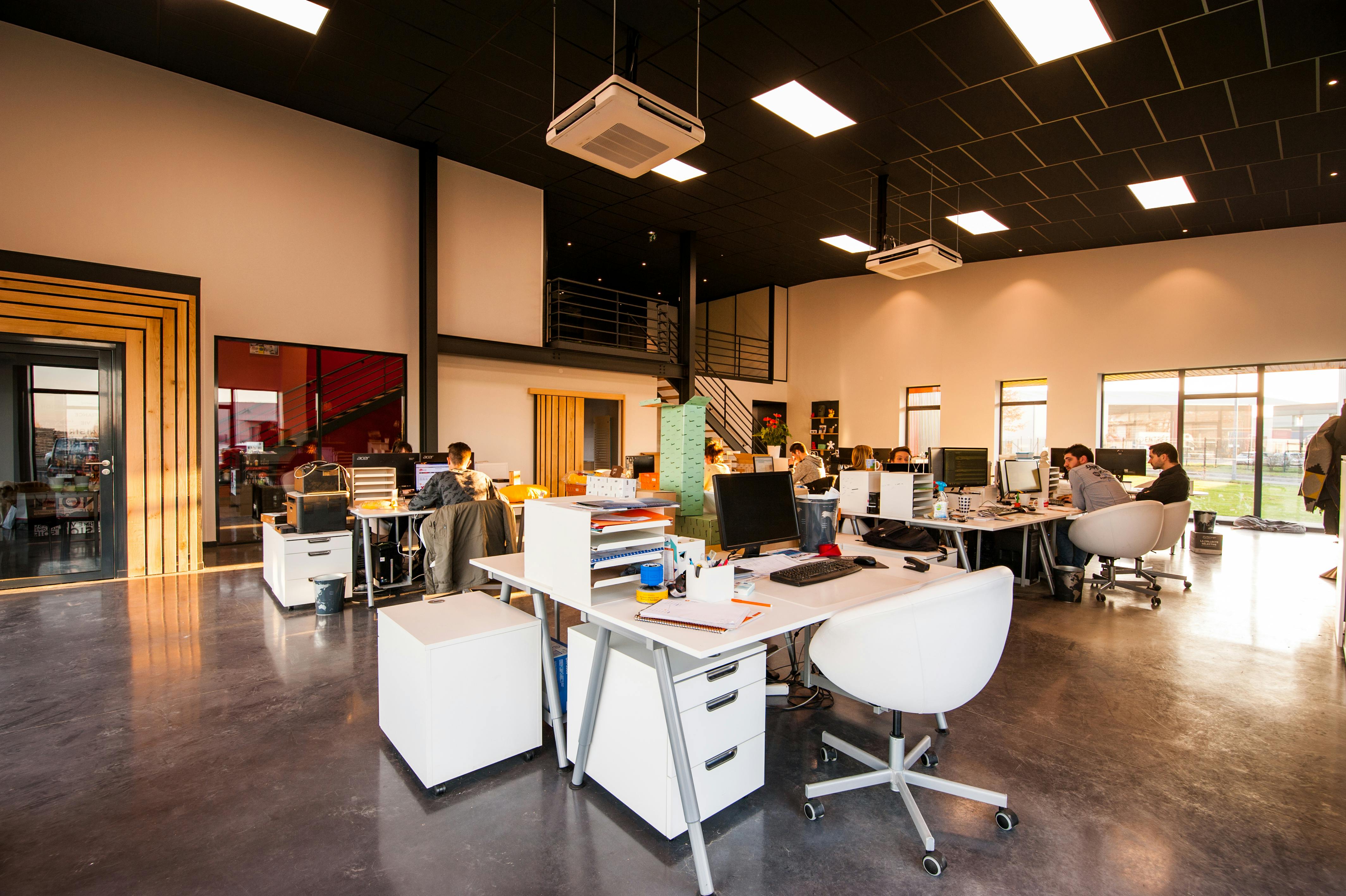 A modern open-plan office with employees working at their desks in a ServiceNow partner's workplace.