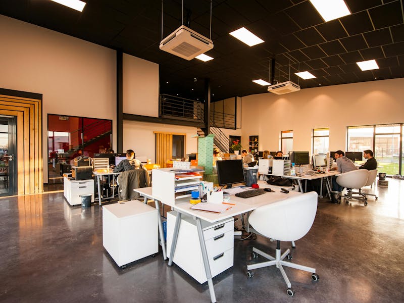 A modern open-plan office with employees working at their desks in a ServiceNow partner's workplace.