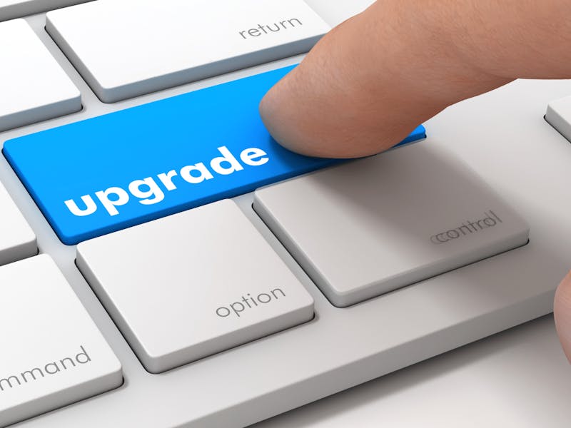 A finger pressing a blue upgrade key on a keyboard for a ServiceNow platform upgrade.