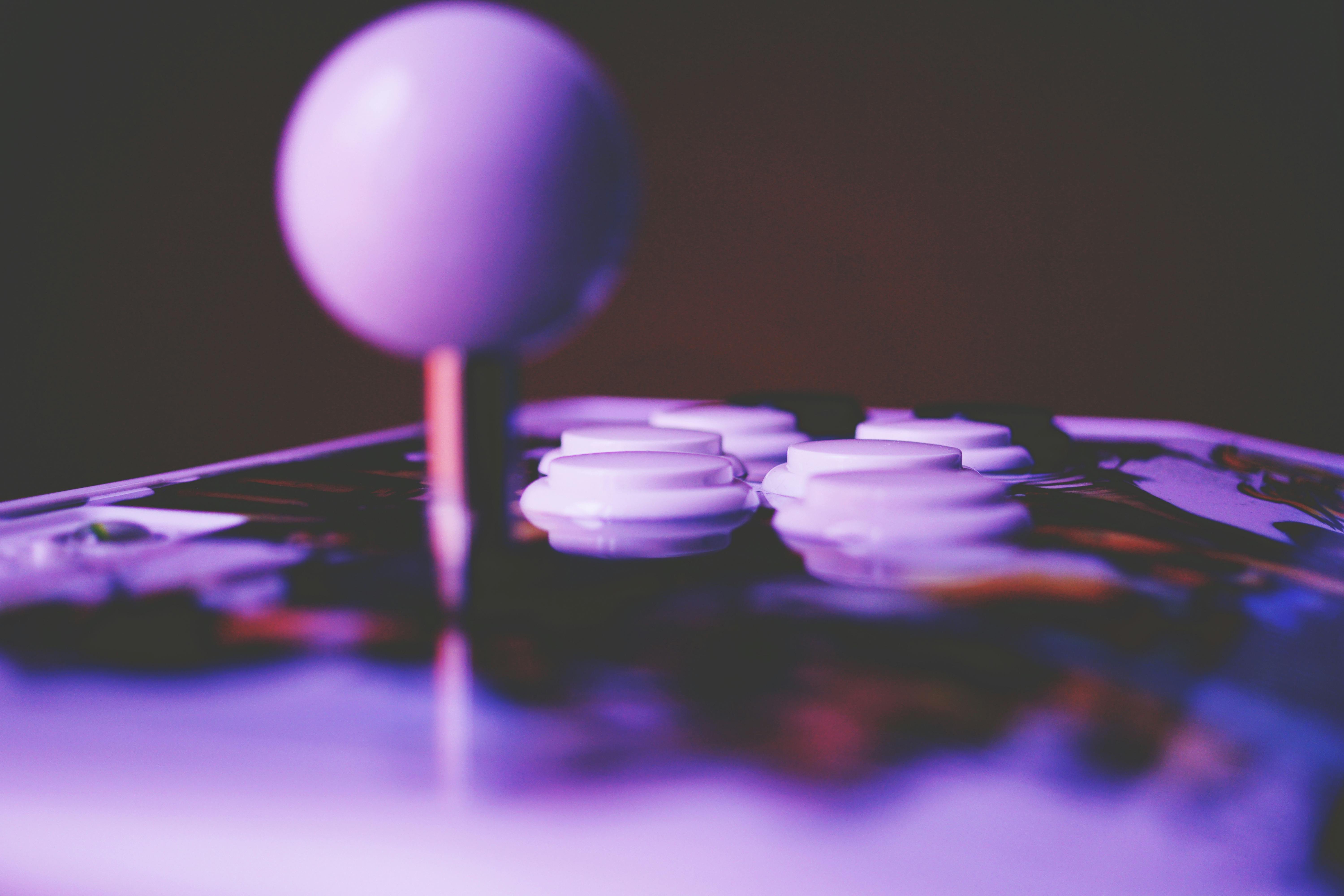 Close-up of an arcade joystick and buttons under purple light, representing a Pacman CMDB theme for ServiceNow.