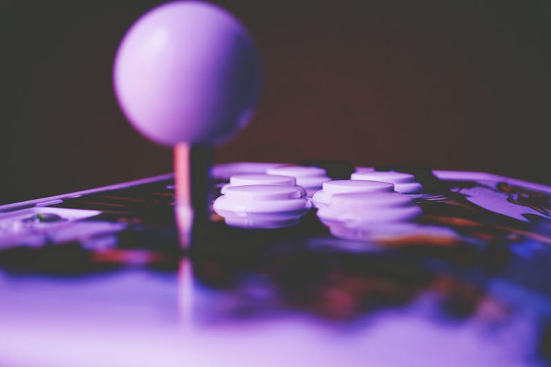 Close-up of an arcade joystick and buttons under purple light, representing a Pacman CMDB theme for ServiceNow.