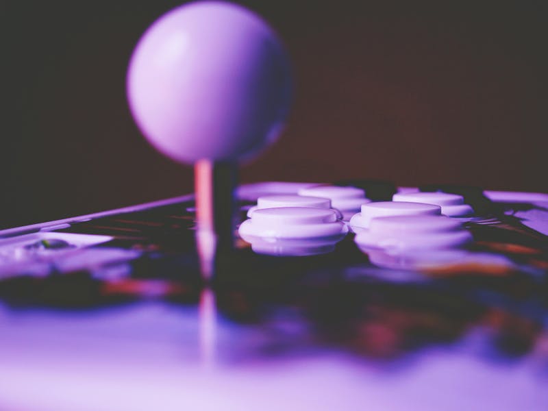 Close-up of an arcade joystick and buttons under purple light, representing a Pacman CMDB theme for ServiceNow.