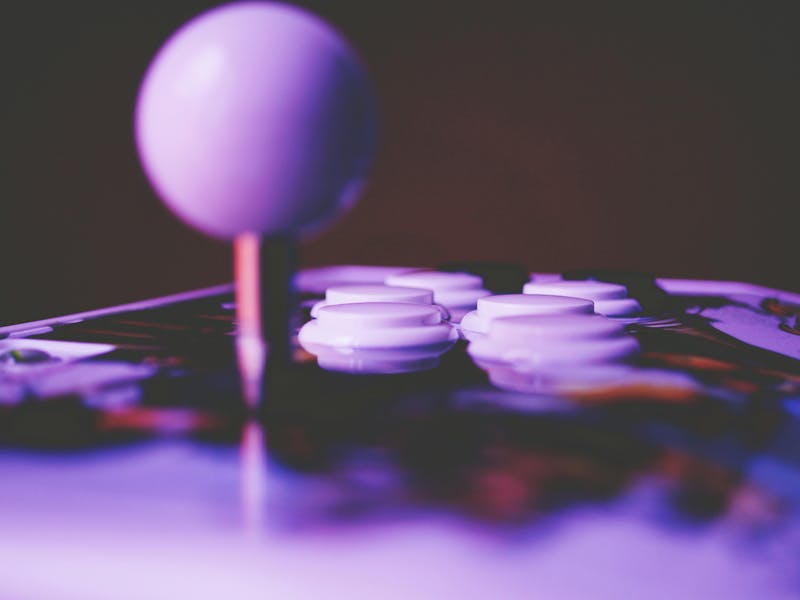 Close-up of an arcade joystick and buttons under purple light, representing a Pacman CMDB theme for ServiceNow.
