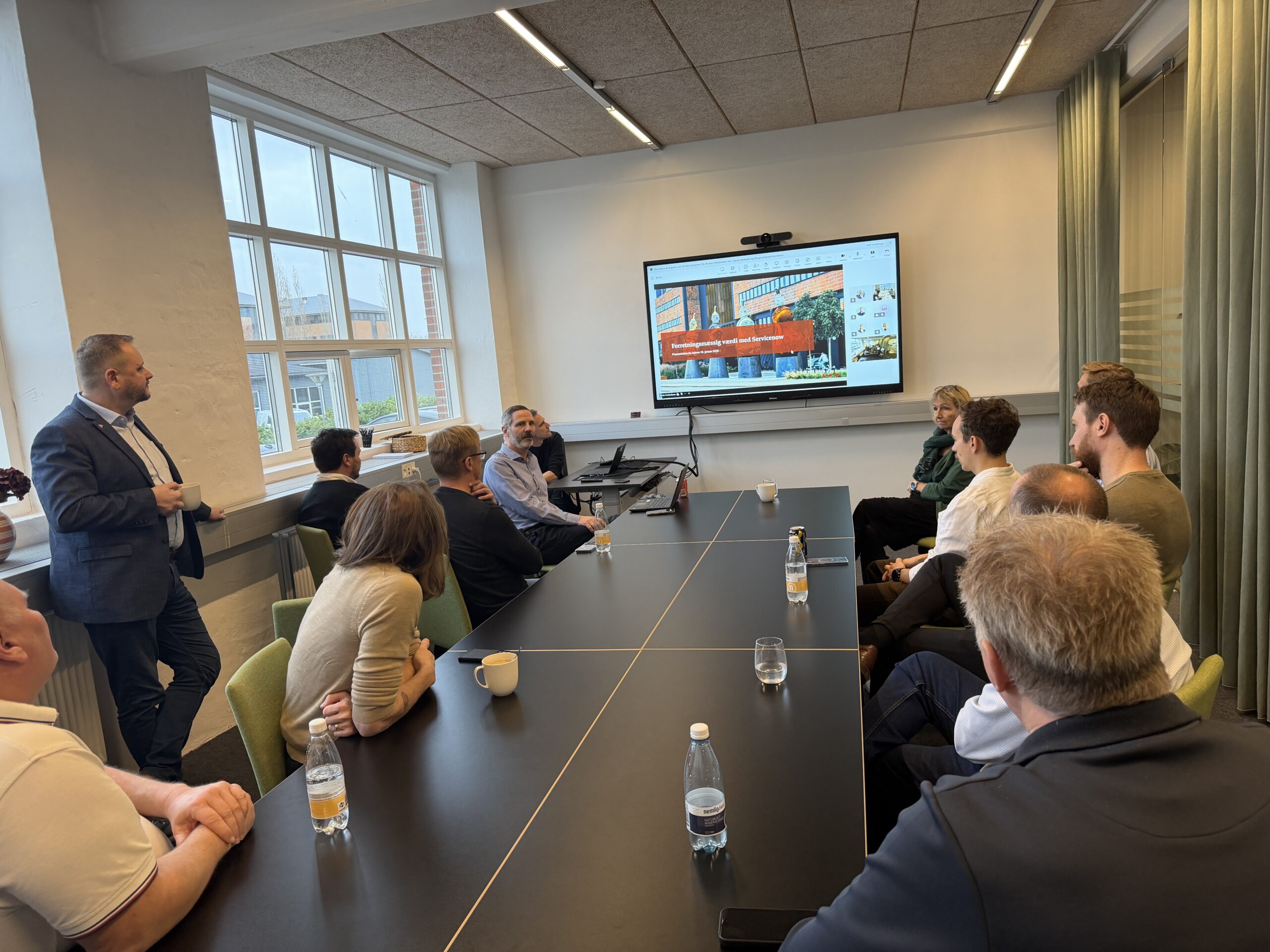 A group of people in a meeting room attending a ServiceNow presentation.