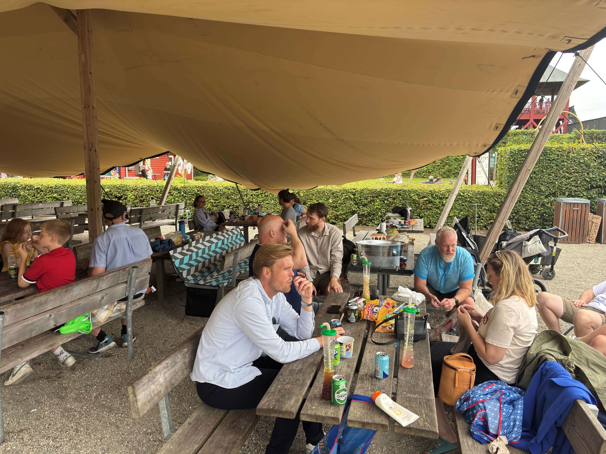 A group of people from ServiceNow partner Adeno gathered under a large canopy at Egeskov Castle for a family day event.