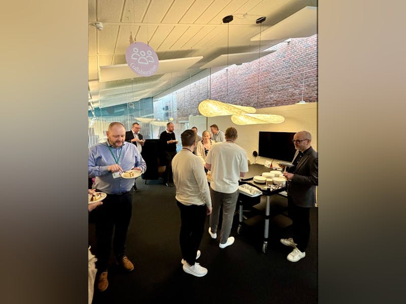A group of people in an office celebrating a ServiceNow CMDB and CSDM go-live event with cake.
