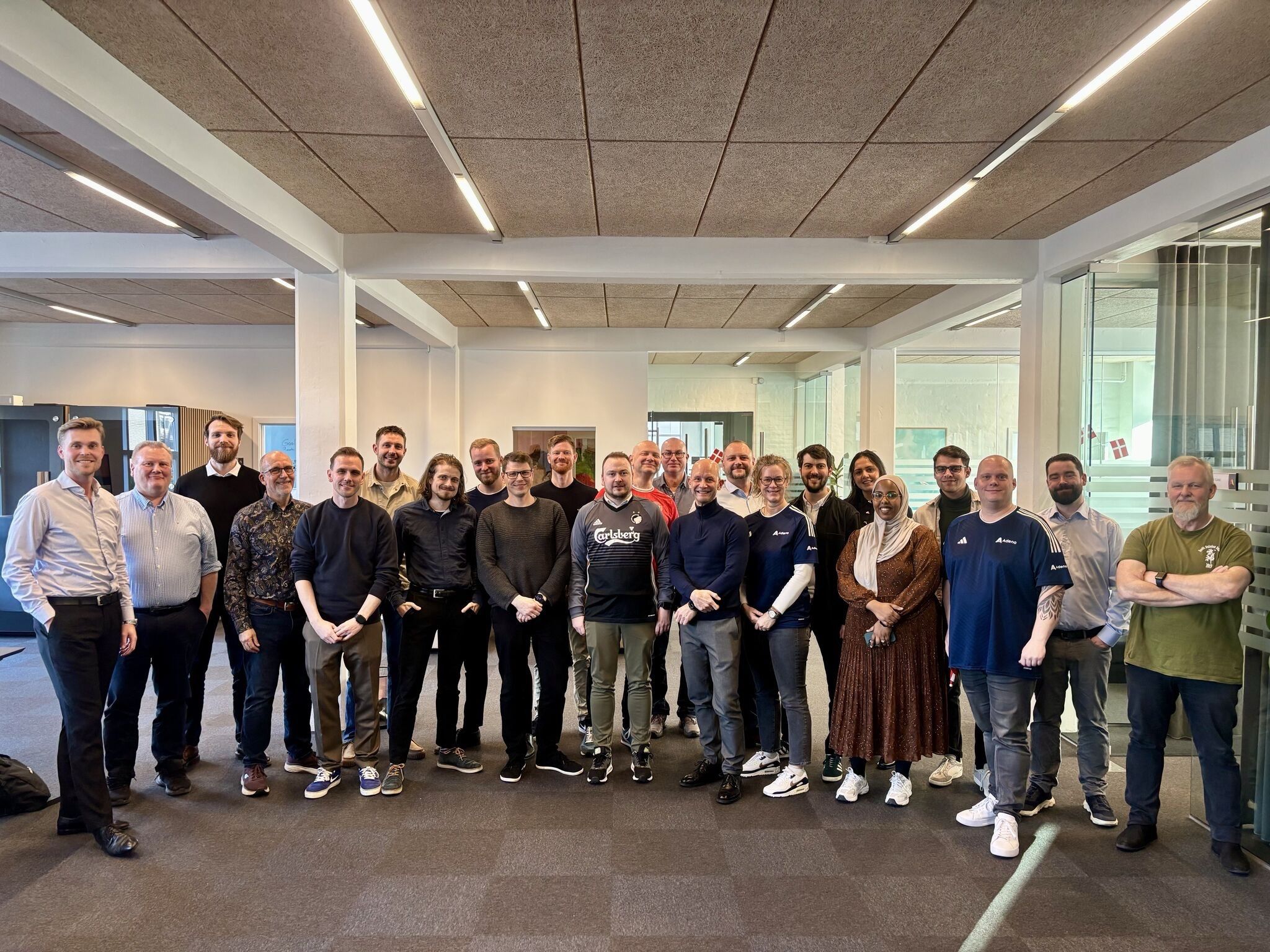 A group of Adeno employees, a ServiceNow partner, posing for a photo in an office to celebrate the company's third anniversary.