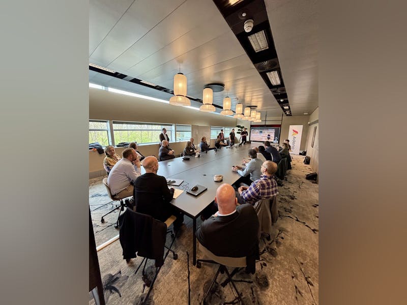 Professionals at a networking event and presentation in a modern conference room hosted by Adeno, a ServiceNow partner.
