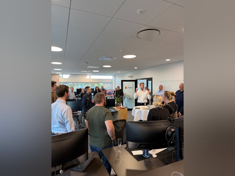 A group of people gathered in an office for a housewarming event at Adeno, a ServiceNow partner.