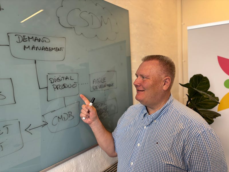 A man pointing at a whiteboard with a ServiceNow CSDM diagram.