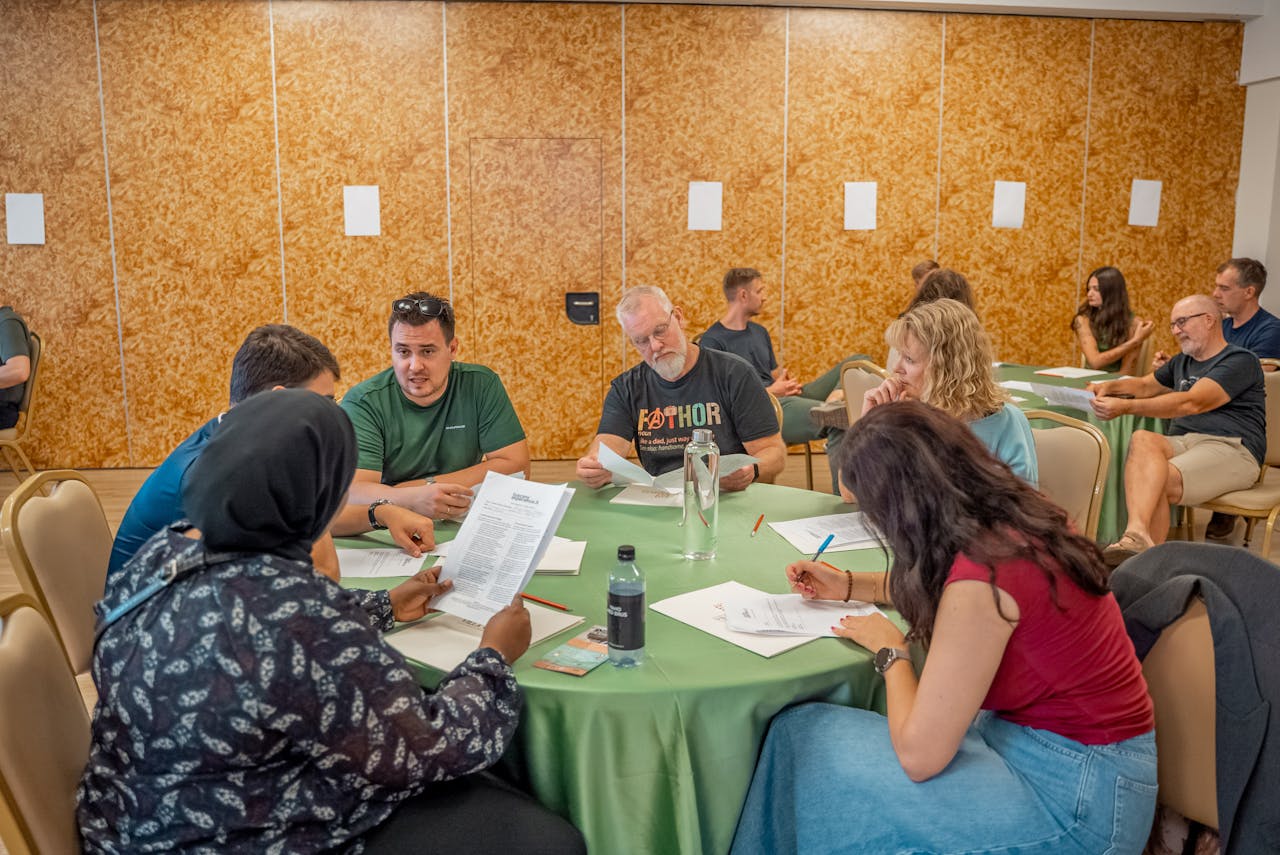 A group of people sitting around a table reviewing documents during a ServiceNow workshop.