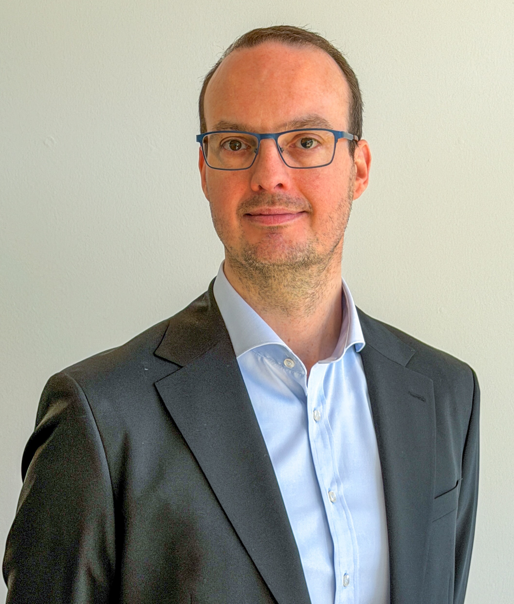 Portrait of Morten Kær Schøler, a ServiceNow professional, wearing a suit and glasses.
