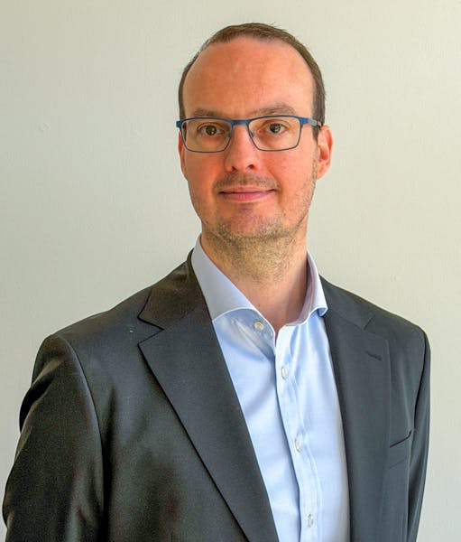Portrait of Morten Kær Schøler, a ServiceNow professional, wearing a suit and glasses.