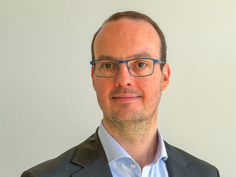 Portrait of Morten Kær Schøler, a ServiceNow professional, wearing a suit and glasses.