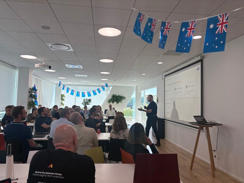A presenter speaking to an audience at a ServiceNow Australia release event in a modern office.