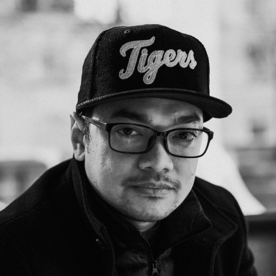 Black and white portrait of Zander Croox, a ServiceNow Platform owner, wearing glasses and a Tigers baseball cap.
