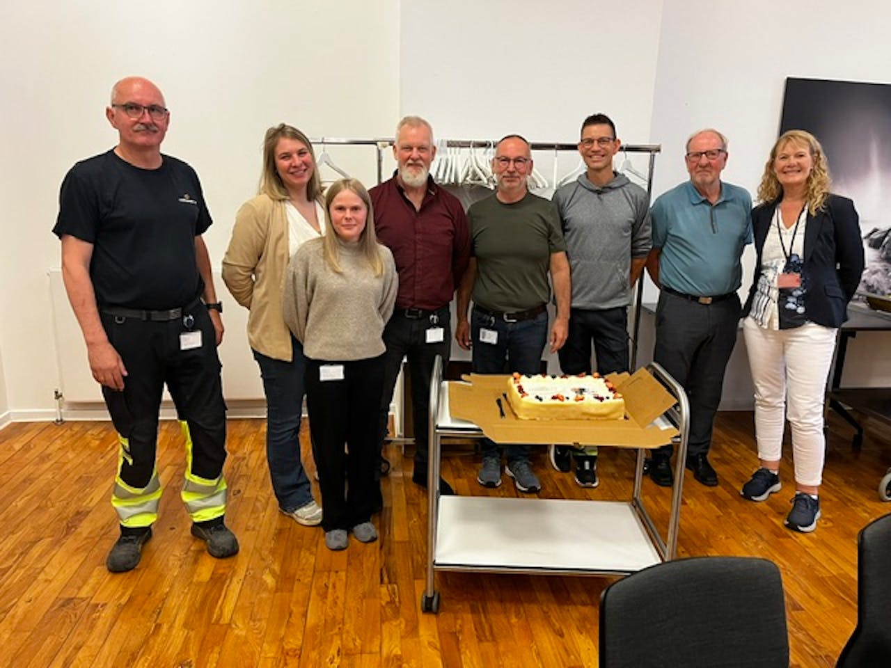 Eight people standing in a room with a cake on a cart celebrating a ServiceNow project go-live.