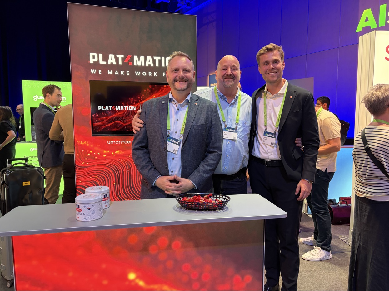 Three men standing behind a Plat4mation booth at a ServiceNow event.