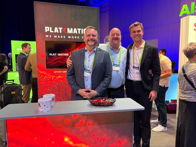 Three men standing behind a Plat4mation booth at a ServiceNow event.