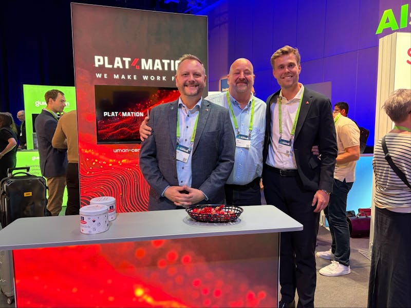 Three men standing behind a Plat4mation booth at a ServiceNow event.