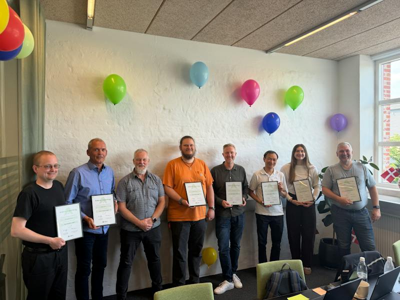 Eight people holding certificates at the Next Academy 2026 graduation for ServiceNow Partner Adeno in a room with balloons."