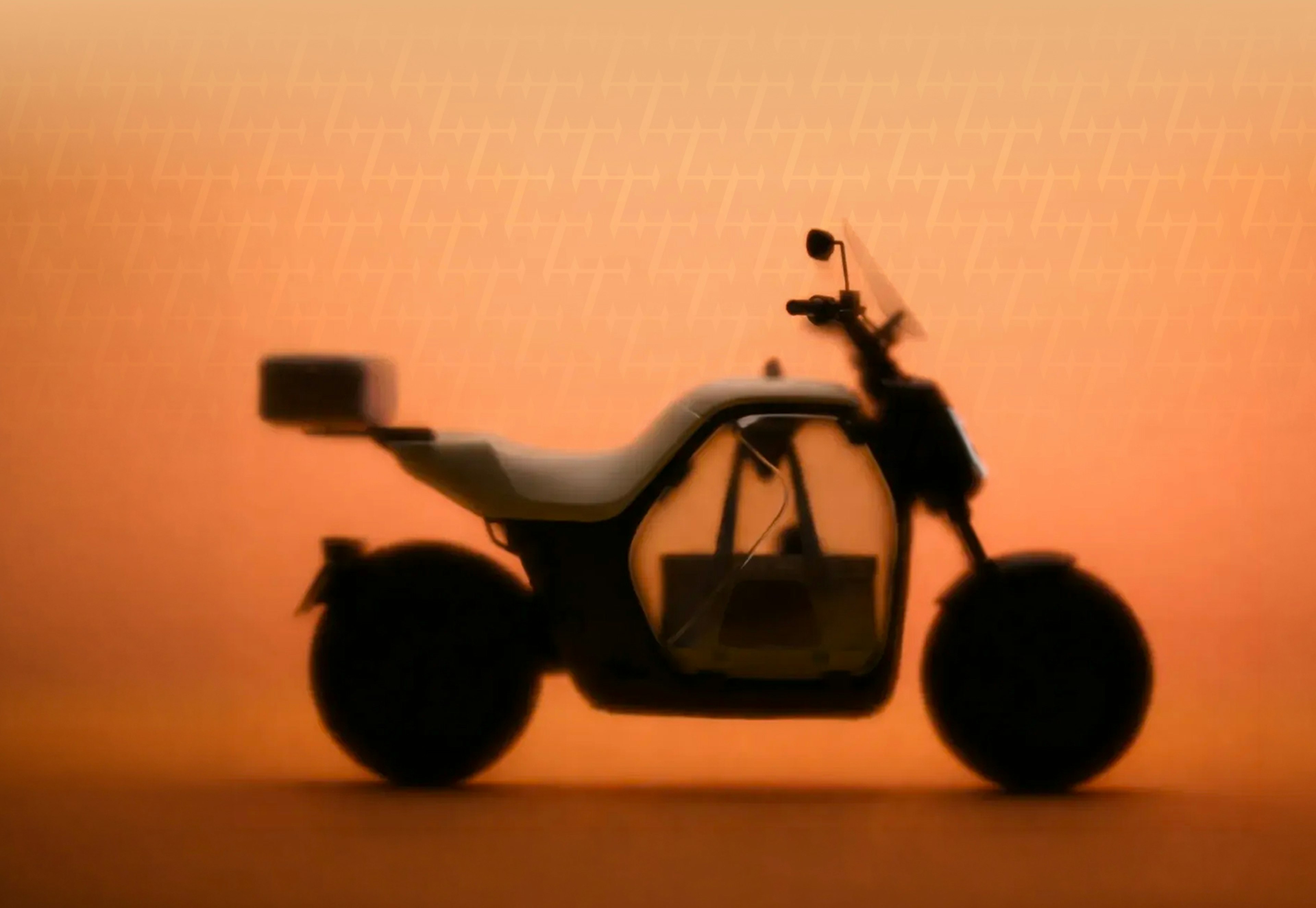 La silueta de una motocicleta sobre un fondo de atardecer anaranjado.