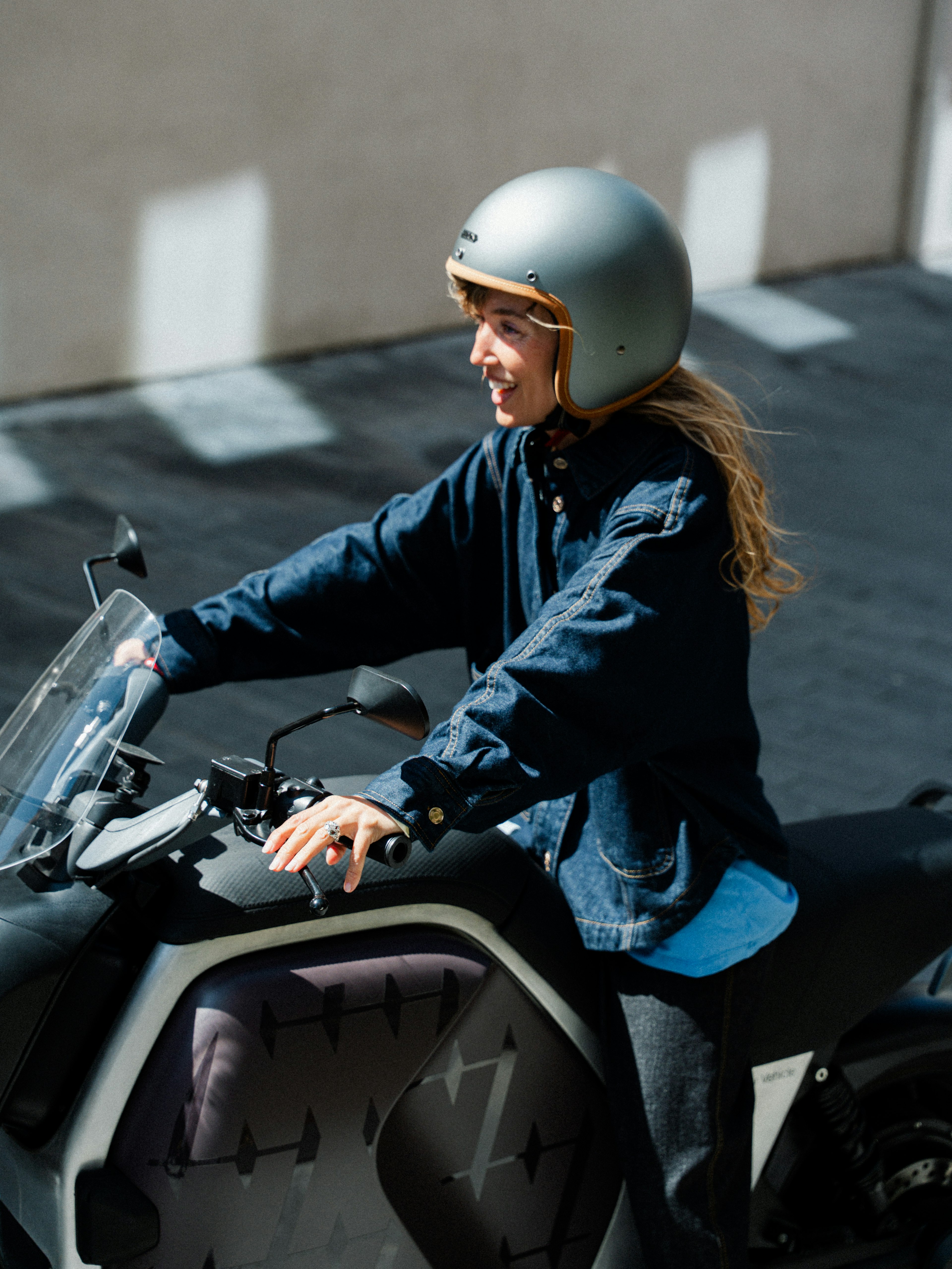 Una persona che indossa il casco, in sella a una moto in una giornata di sole.