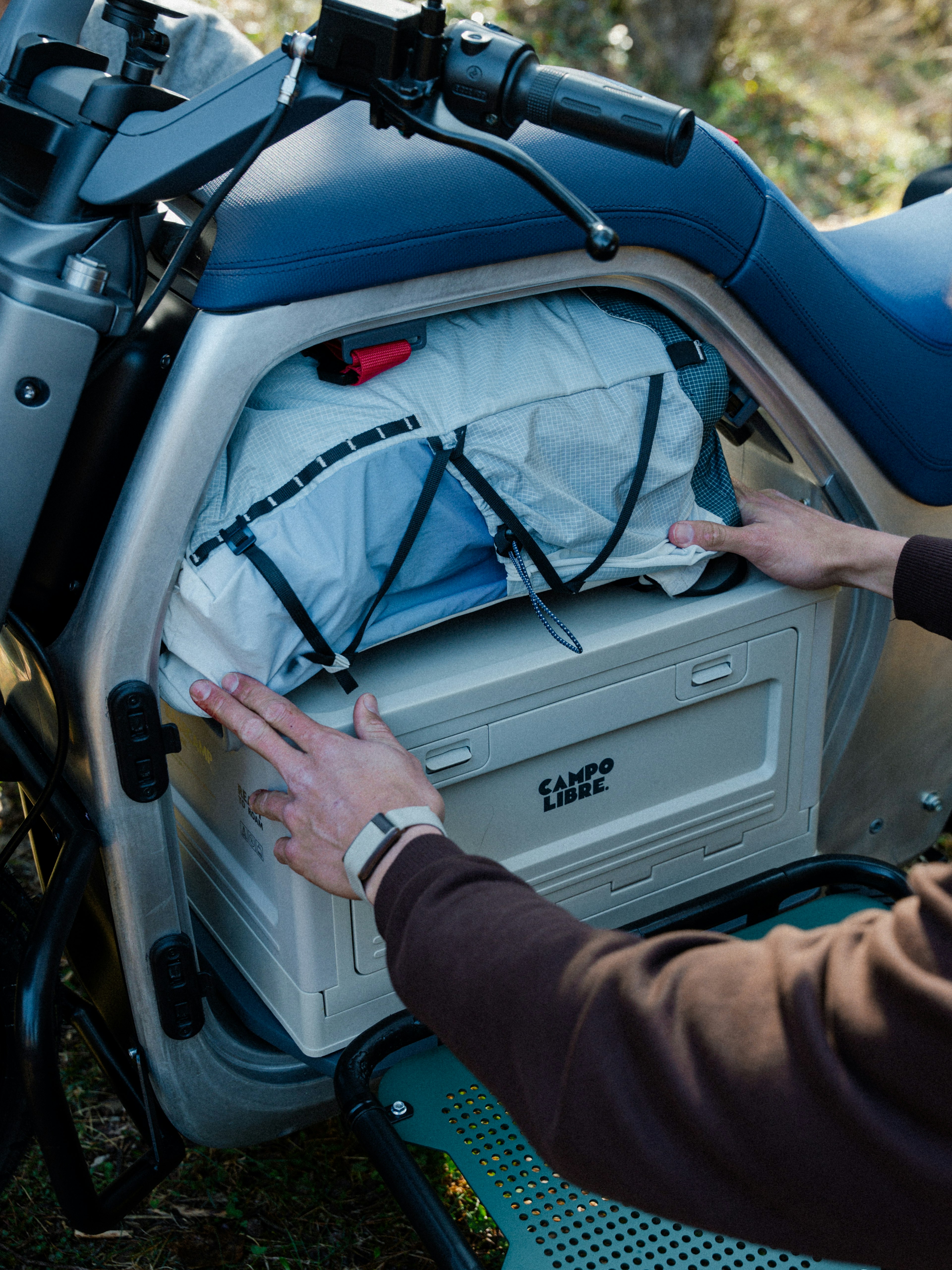 Una persona trasporta una borsa termica bianca con una rete elastica su una moto.