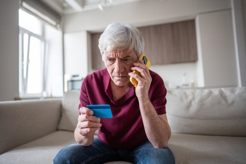 older man on the phone looking at his credit card