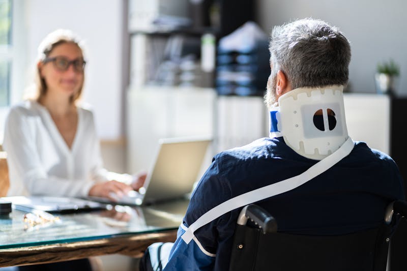 man wearing a neck brace, talking to a personal injury lawyer