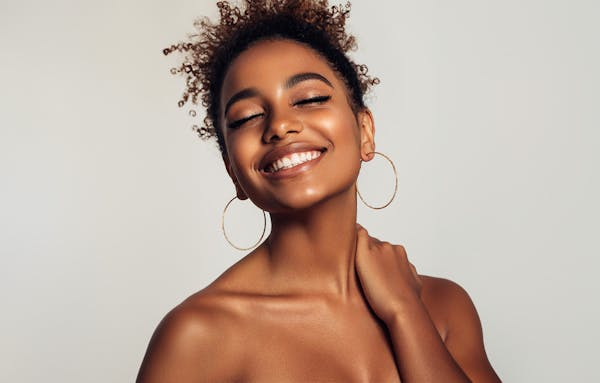 woman smiling with eyes closed with hands on neck