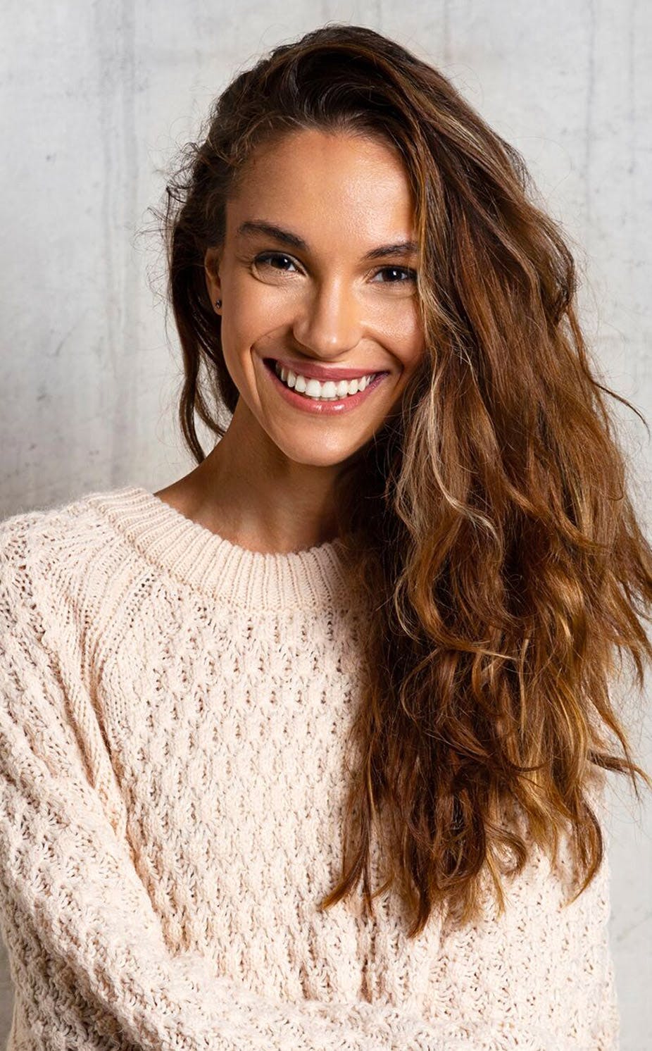 woman with wavy hair wearing a white sweater