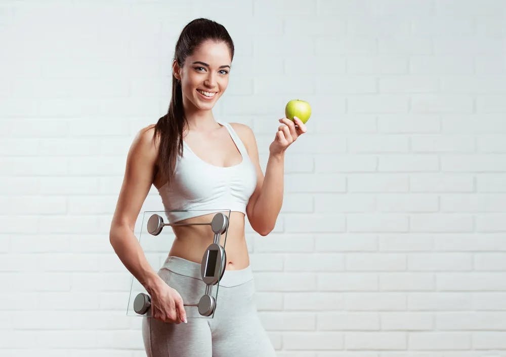 woman holding an apple and a scale