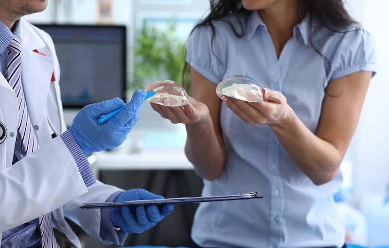 woman holding breast implants