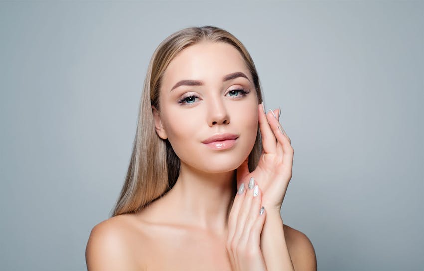 Blonde woman tocuhing her cheek