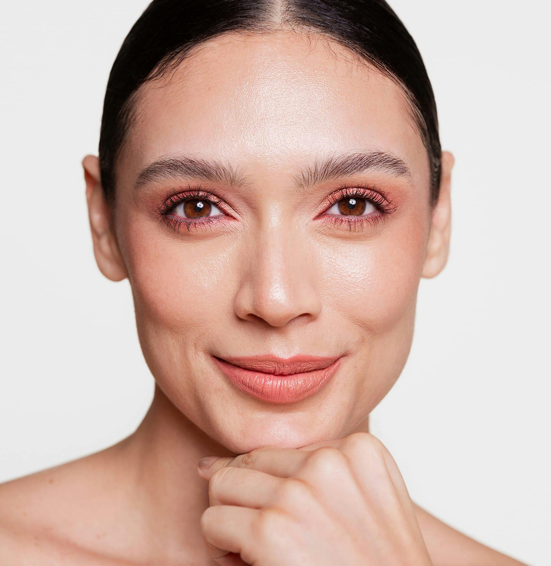 close up on woman with makeup resting chin on hand