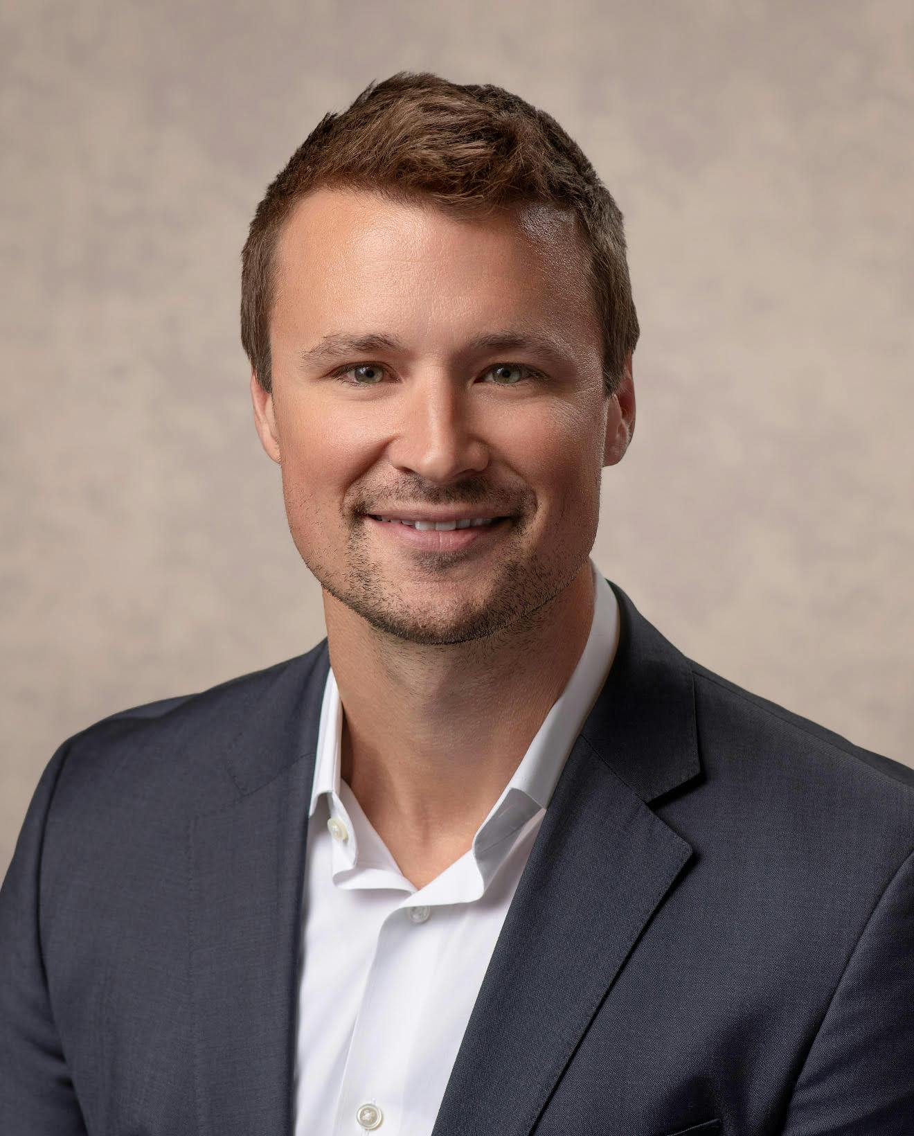 Daniel Straka smiling in a suit and white button down shirt