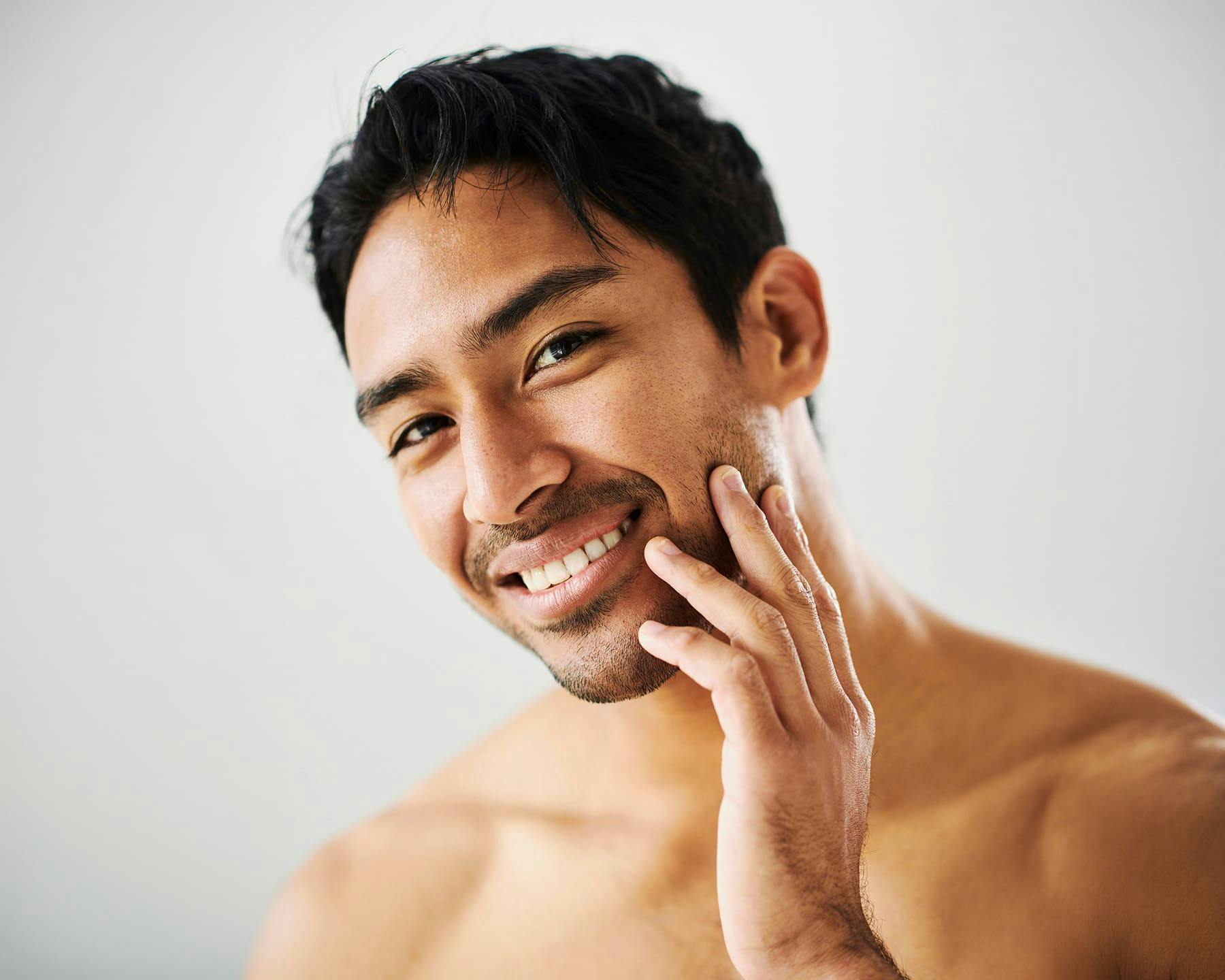 Man smiling and touching his face