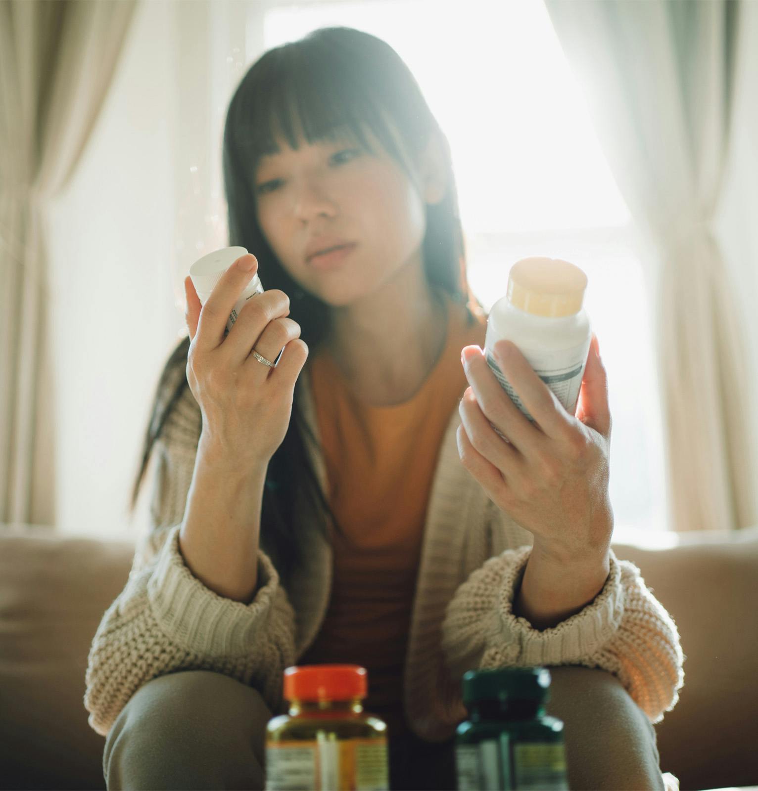 woman looking at pill bottle labels